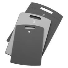 Three dark gray cutting boards stacked, each with handle cutout
