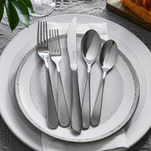 Stainless steel flatware on round plate: forks, knife, and spoons in a set