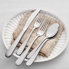 Stainless steel flatware on plate with knife, forks, and spoon on a linen napkin