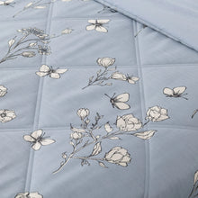 Close-up quilted blue down alternative blanket with white floral and butterfly print