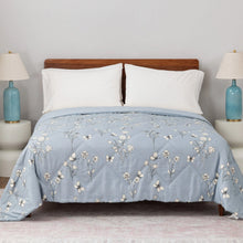 Blue down alternative blanket with white floral and butterfly print, neatly spread