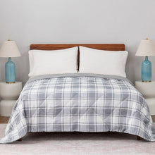 Grey plaid down alternative blanket covering the bed