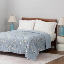 Blue down alternative blanket with white floral and butterfly print on a bed