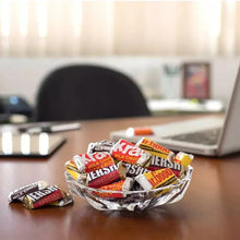 Assorted Hershey's mini chocolate candy bars in a foil-lined bowl on table