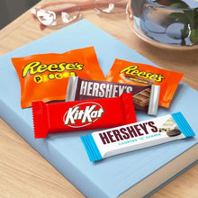 Assorted candy bars on a tray: Reese's Pieces, Kit Kat, and Hershey's