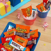 Assorted candy bars in red container with Reese's Pieces, Kit Kat, and Hershey's