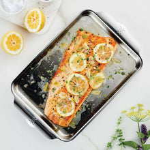 Stainless sheet pan with baked salmon topped with lemon slices and herbs