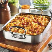 Stainless steel roasting pan filled with baked macaroni and cheese-style dish