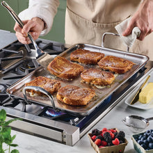 Stainless steel griddle pan with handles, cooking surface, and grilled food