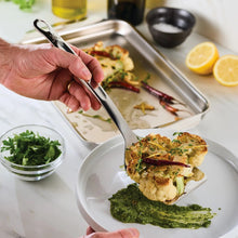 Stainless steel solid turner being used to lift grilled food from a plate
