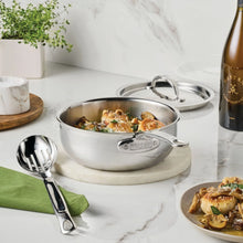 Stainless steel saucier with lid and pour spout, filled with food