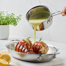 Stainless steel butter warmer pouring melted butter over roasted food