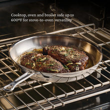 Stainless steel skillet on an oven rack, holding a roast with herbs.
