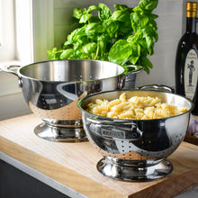 Stainless steel colander on countertop, holding cooked pasta in a perforated bowl