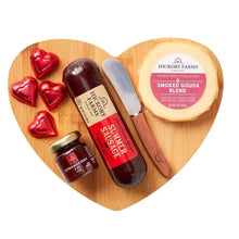 Wood heart charcuterie board with sausages, Smoked Gouda wheel, and condiment jars