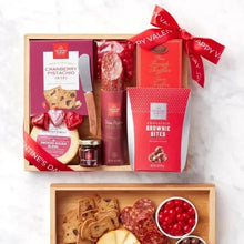 Assorted Valentine gift set in open wooden box with wrapped chocolates and snack items