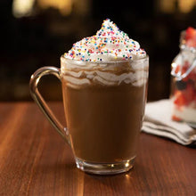 Glass mug of cappuccino with whipped cream and multicolor sprinkles