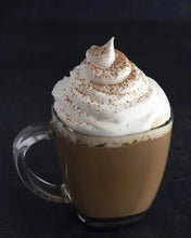 Glass mug of cappuccino with whipped cream and cocoa dusting