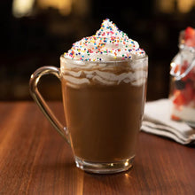 Glass mug cappuccino topped with whipped foam and colorful sprinkles