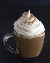 Glass mug of cappuccino with foamy swirl and light cocoa dust