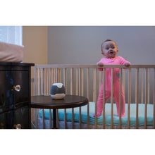 Baby sound machine with white top and gray speaker base on bedside table