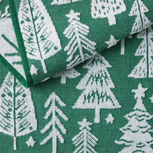 Green kitchen towel with white tree-and-foliage pattern and folded corner.