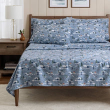Blue winter-scene cotton sheets and pillowcases spread across a bed
