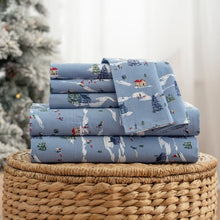 Folded blue cotton sheets with winter village and sledding print