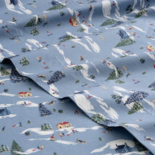 Close-up of blue cotton sheet fabric printed with snowy scenes and sledders