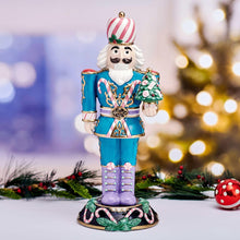 Teal nutcracker figure with purple legs, striped hat, holding a green holiday tree