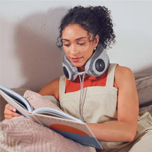 Portable neck massager with gray strap and round black speaker on a person’s neck