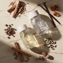Glass scent bottles with golden caps and cinnamon-style fragrance sticks on a tray