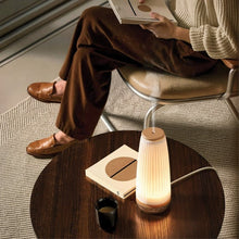 Ceramic diffuser on a round table with lit glow beside a mug and book