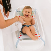 White baby bathtub with blue-trimmed sling holding a smiling infant