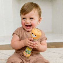 Infant laughing while holding an orange fox rainstick rattle toy