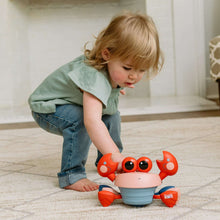 Musical crawling crab toy with red side arms, pale pink head, blue base, black eyes