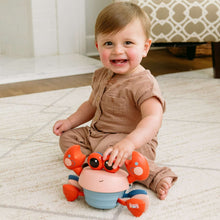Musical crawling crab toy with red arms, pale pink head, blue base, and black eyes
