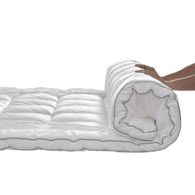 Rolled white polyester-filled mattress topper pad with stitched baffles