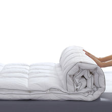 Rolled white feather bed topper with quilted padding and fabric cover