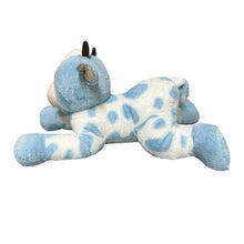 Blue and white cow plush lying down, front paws extended, horns on head