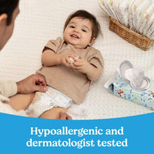 Huggies Natural Care baby wipes pack and dispenser near a baby