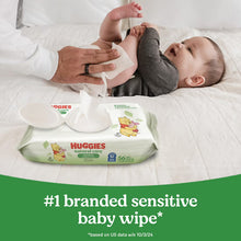 Sensitive baby wipes packet on bed as adult cleans infant with wipe