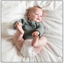 Baby wearing a white diaper with light prints and blue trim, hands raised
