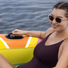 Inflatable island with side handle and teal deck stripe next to seated woman