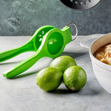 Green citrus squeezer with ridged cone press and lever handle, near limes