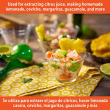 Green lime squeezer pressing fruit over a clear cup
