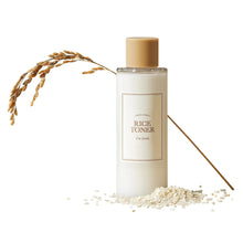 Toner bottle with gold cap, white body, and scattered rice grains