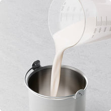 Pouring pale ice cream mixture into metal churn bowl of the ice cream maker