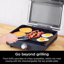 Indoor electric grill with open lid, griddle cooking bacon, eggs, and pancakes