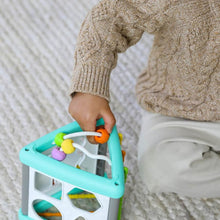 Child hand on teal and white activity triangle shape sorter with colorful shapes